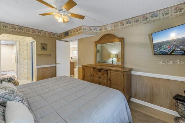 bedroom with a wainscoted wall and a ceiling fan