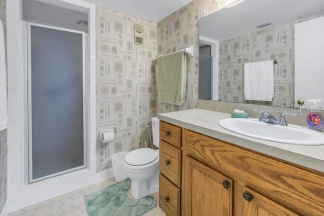 bathroom with a stall shower, vanity, toilet, and wallpapered walls