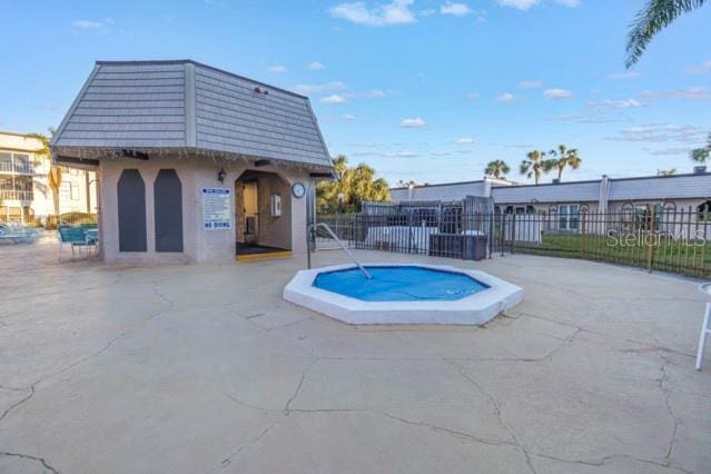 view of pool with a patio area, fence, and a hot tub