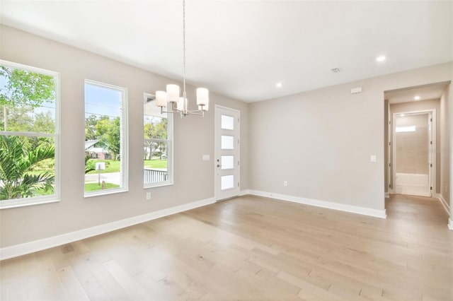 unfurnished dining area featuring light wood finished floors, baseboards, a chandelier, and recessed lighting