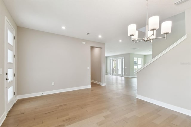 unfurnished room with visible vents, baseboards, light wood-type flooring, a notable chandelier, and recessed lighting