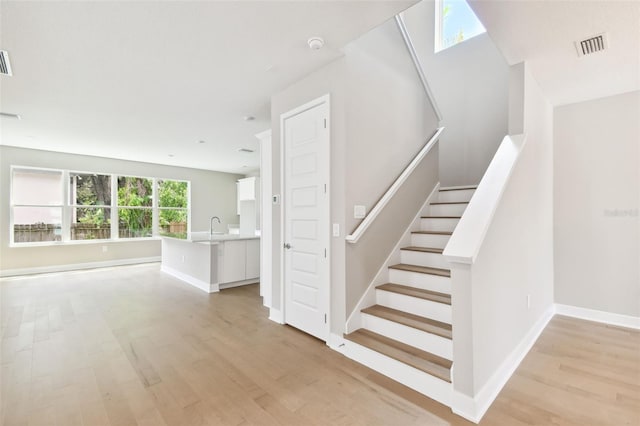 stairway featuring wood finished floors, visible vents, and baseboards