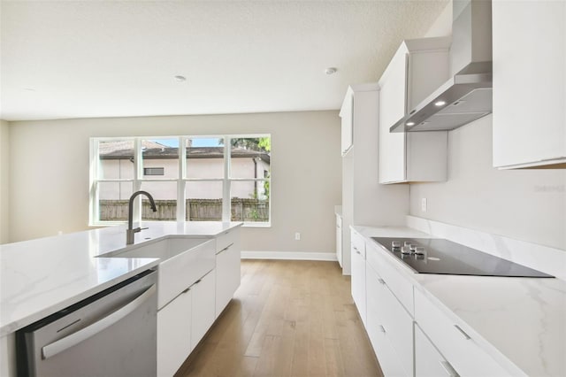 kitchen featuring dishwasher, wall chimney exhaust hood, black electric cooktop, light wood-type flooring, and white cabinetry