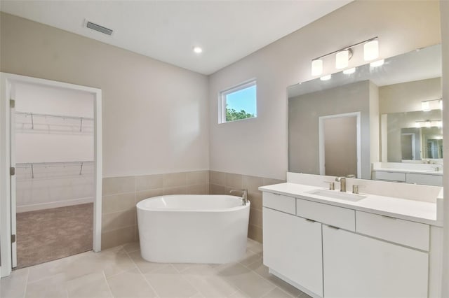 bathroom with tile patterned flooring, visible vents, a freestanding bath, and vanity