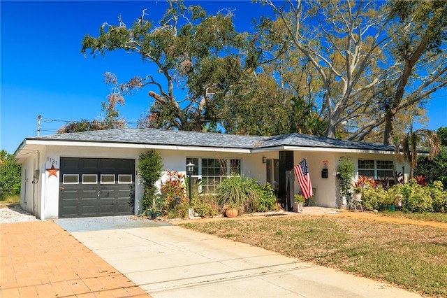 ranch-style house with concrete driveway, a front lawn, an attached garage, and stucco siding