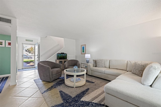 living room with visible vents, a textured ceiling, and light tile patterned floors