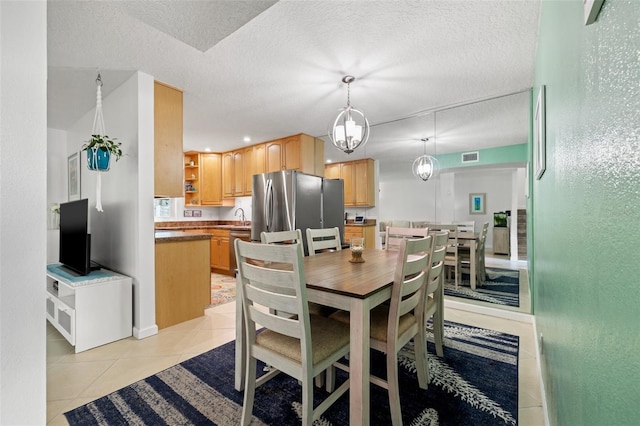 dining room with light tile patterned floors, a textured ceiling, and visible vents