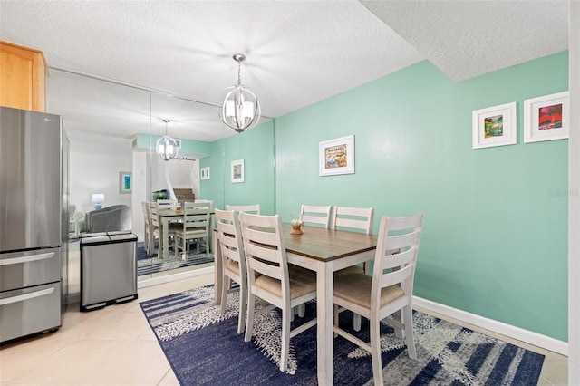 dining space with a chandelier, light tile patterned flooring, a textured ceiling, and baseboards