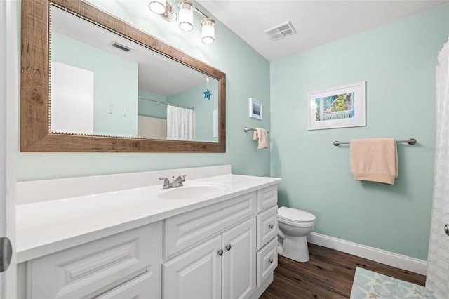 full bath featuring toilet, wood finished floors, vanity, visible vents, and baseboards