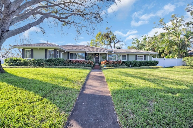 single story home featuring a tile roof, fence, a front lawn, and stucco siding