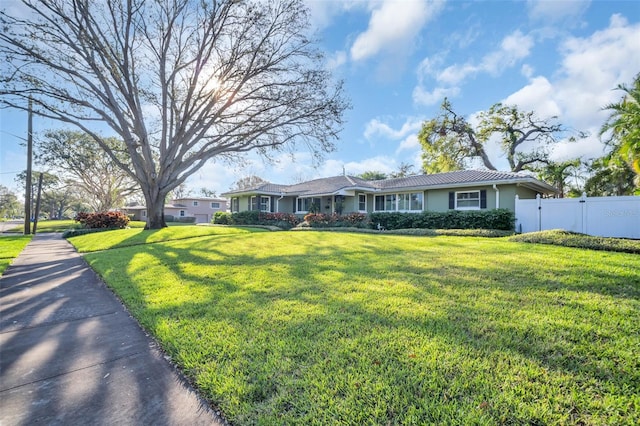 ranch-style home with a tile roof, a gate, fence, a front lawn, and stucco siding