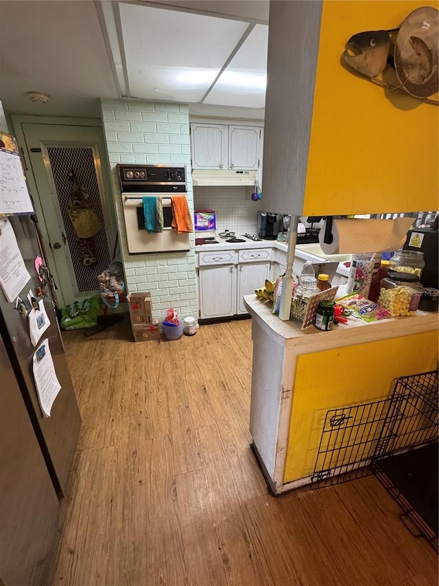 kitchen with light wood-style floors, white appliances, light countertops, and under cabinet range hood