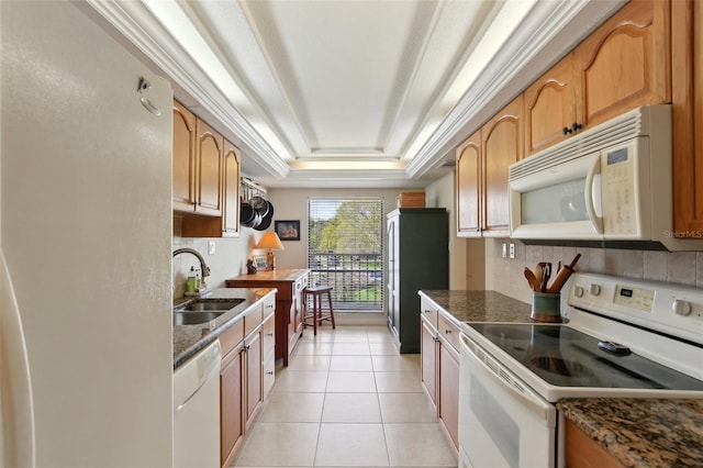 kitchen featuring light tile patterned floors, white appliances, a sink, ornamental molding, and a tray ceiling