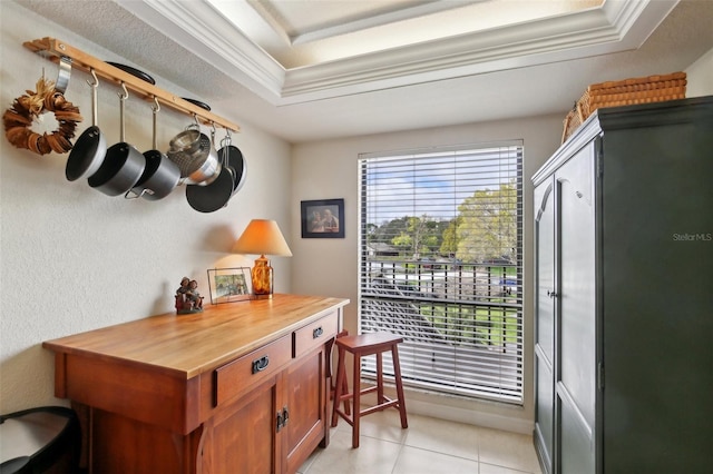 doorway to outside featuring light tile patterned floors, ornamental molding, and a raised ceiling