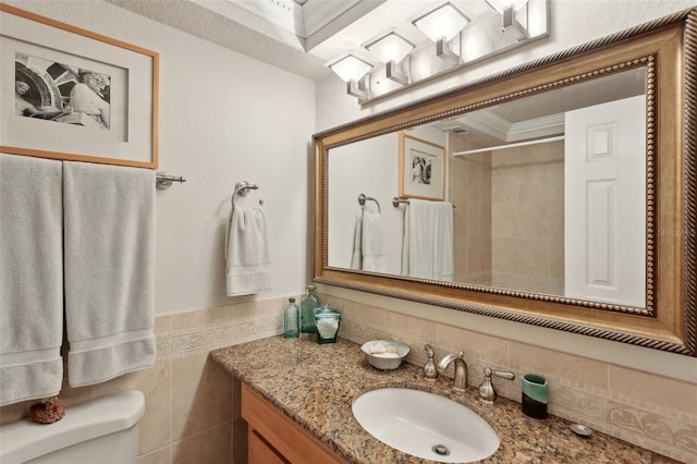 full bath featuring toilet, vanity, tile walls, wainscoting, and a tile shower