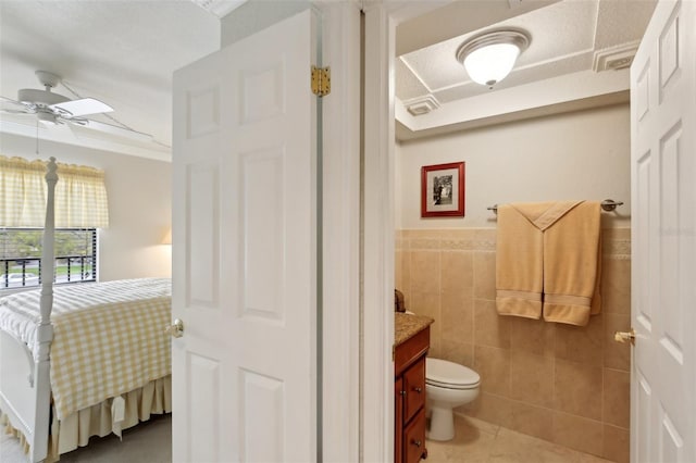 bathroom with tile walls, toilet, ceiling fan, vanity, and tile patterned flooring