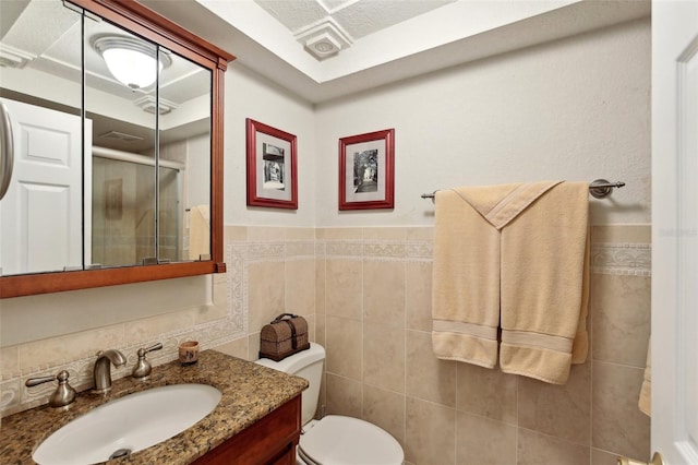 full bath with a wainscoted wall, tile walls, toilet, a shower stall, and vanity