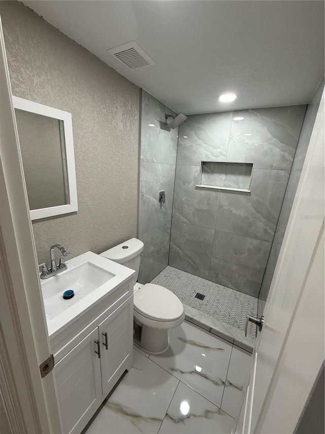 bathroom featuring a stall shower, marble finish floor, visible vents, and a textured wall