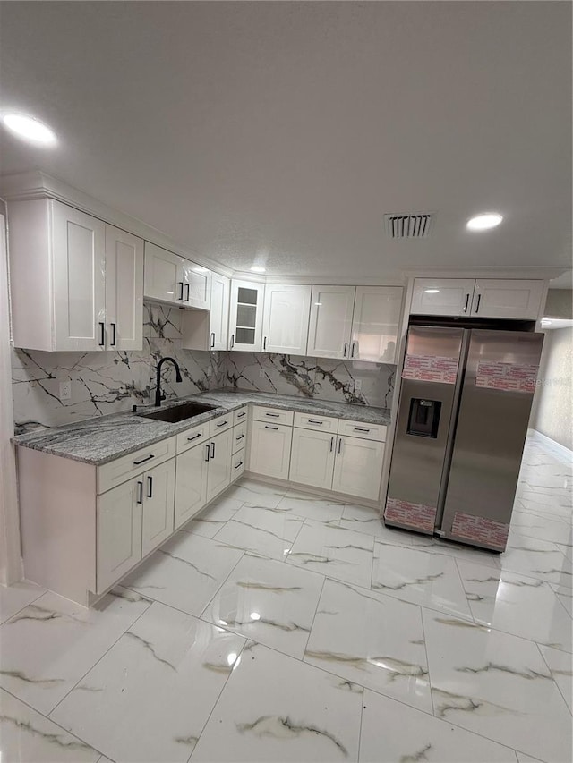 kitchen featuring a sink, visible vents, white cabinets, marble finish floor, and stainless steel fridge with ice dispenser