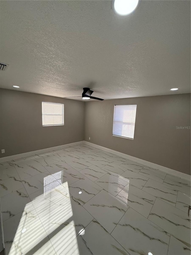 empty room with visible vents, baseboards, a ceiling fan, marble finish floor, and a textured ceiling