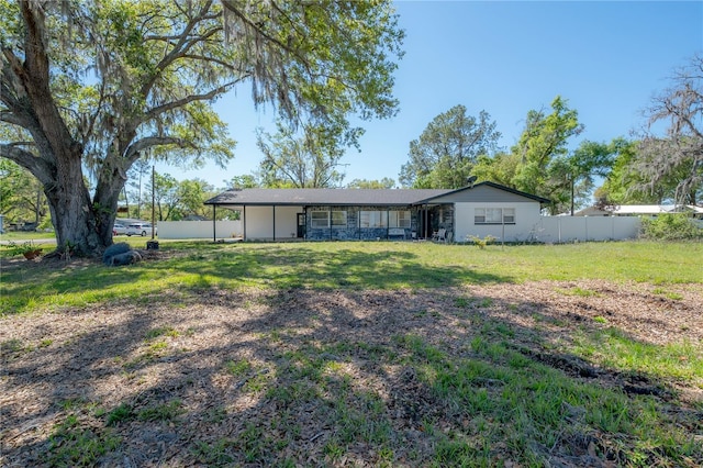 rear view of property featuring fence and a lawn