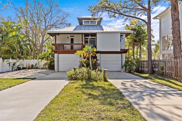 view of front of property featuring a garage, driveway, fence, and metal roof