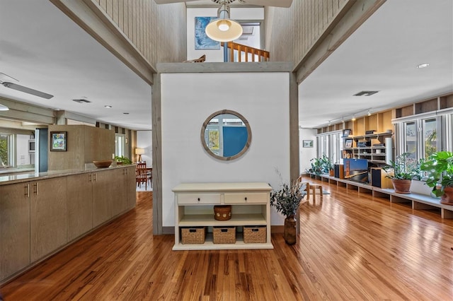 entrance foyer with ceiling fan, a high ceiling, wood finished floors, and visible vents