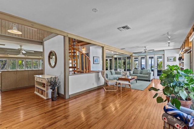 interior space featuring french doors, light wood finished floors, visible vents, ceiling fan, and stairs