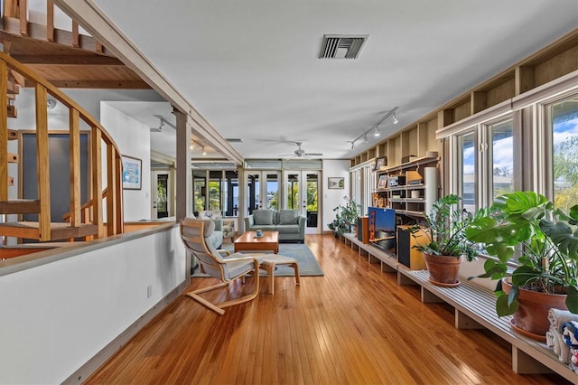 living area featuring a wealth of natural light, hardwood / wood-style flooring, visible vents, and a ceiling fan