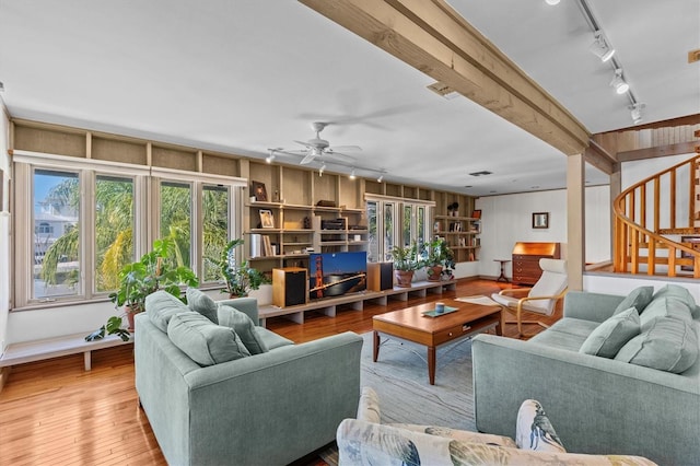 living room featuring stairs, a ceiling fan, track lighting, beamed ceiling, and hardwood / wood-style flooring