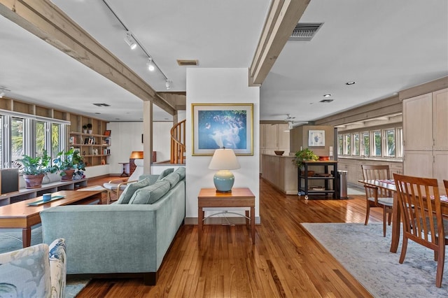 living room featuring rail lighting, visible vents, and hardwood / wood-style floors