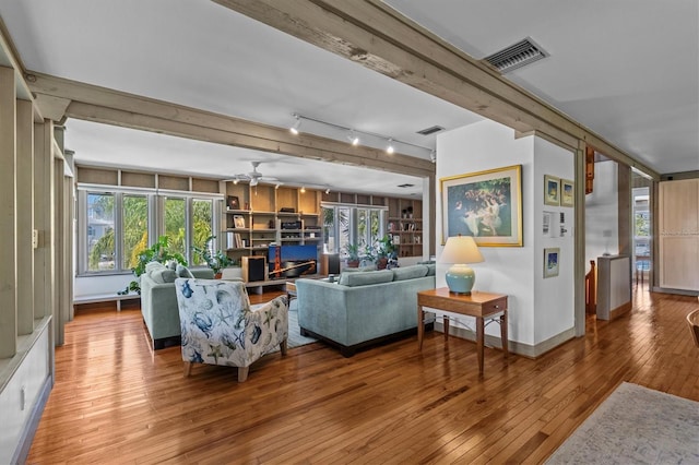 living room featuring wood-type flooring, visible vents, and a healthy amount of sunlight