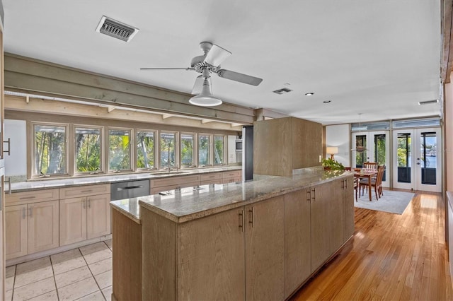 kitchen featuring a center island, french doors, visible vents, and light stone countertops