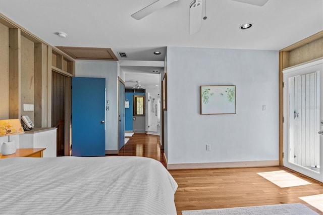 bedroom with baseboards, wood finished floors, visible vents, and attic access