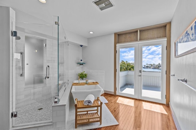 full bathroom with french doors, a soaking tub, visible vents, a shower stall, and hardwood / wood-style floors