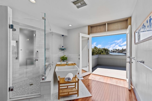 bathroom with recessed lighting, visible vents, a soaking tub, hardwood / wood-style floors, and a stall shower