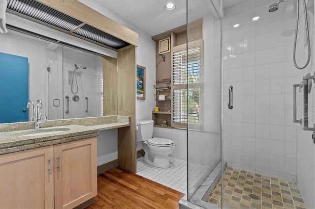 bathroom with vanity, wood finished floors, a shower stall, and toilet