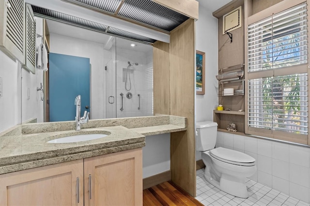 bathroom with tile patterned floors, a shower stall, toilet, and vanity