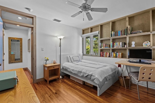 bedroom featuring baseboards, wood finished floors, visible vents, and a ceiling fan