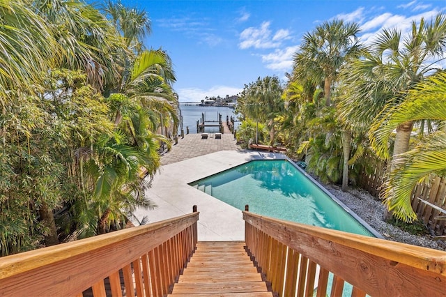 outdoor pool featuring a patio area, a boat dock, and a water view