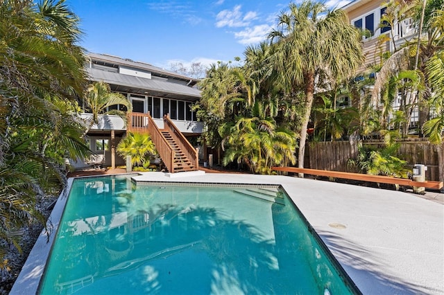 view of swimming pool with a fenced in pool, a sunroom, fence, and stairs