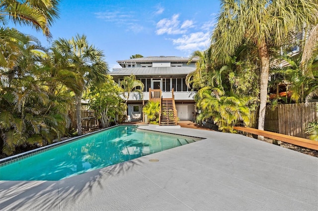 view of pool featuring a fenced in pool, a patio, a sunroom, fence, and stairs