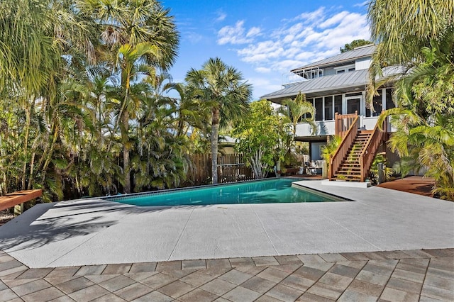 pool with a sunroom, stairs, and a patio