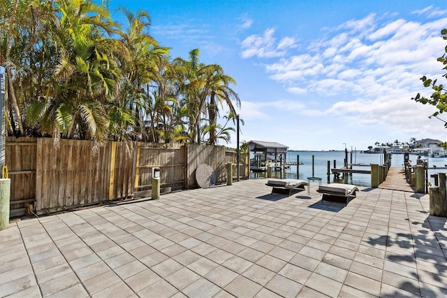 exterior space featuring boat lift, a patio, a water view, and fence