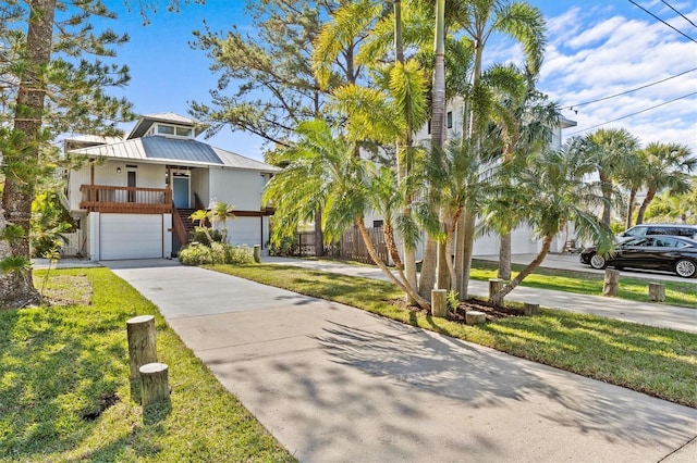 view of front of property with stucco siding, a porch, concrete driveway, stairway, and metal roof