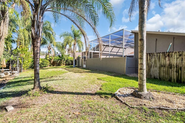 view of yard featuring glass enclosure and fence