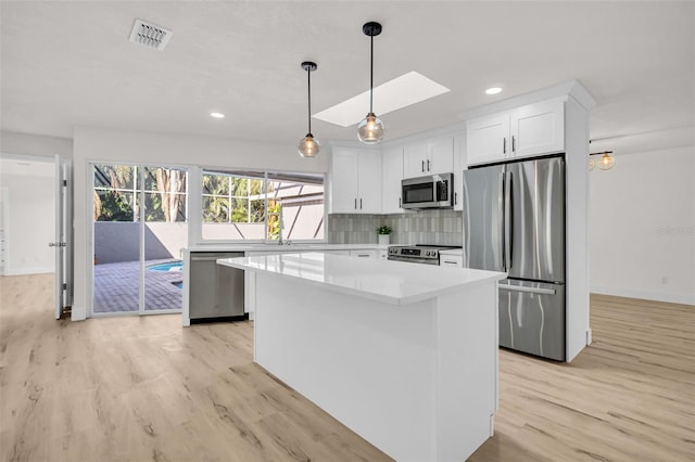 kitchen with appliances with stainless steel finishes, light wood-type flooring, visible vents, and white cabinetry