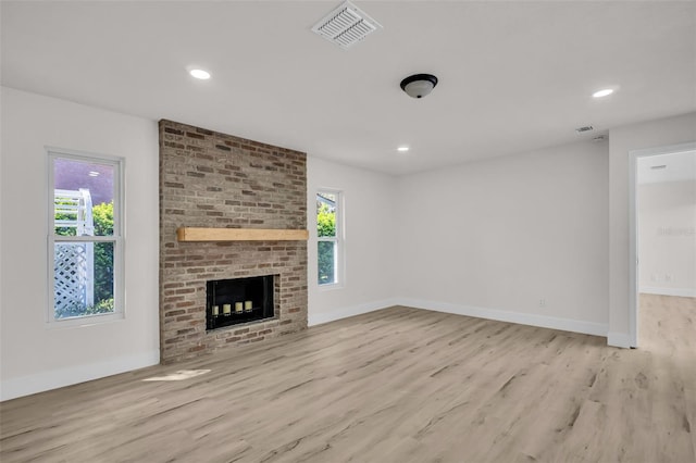 unfurnished living room featuring visible vents, a fireplace, baseboards, and wood finished floors