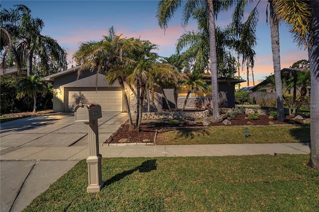 mid-century home featuring driveway, stucco siding, a garage, and a yard