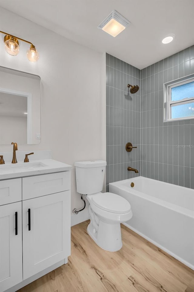 bathroom featuring shower / bath combination, visible vents, toilet, vanity, and wood finished floors